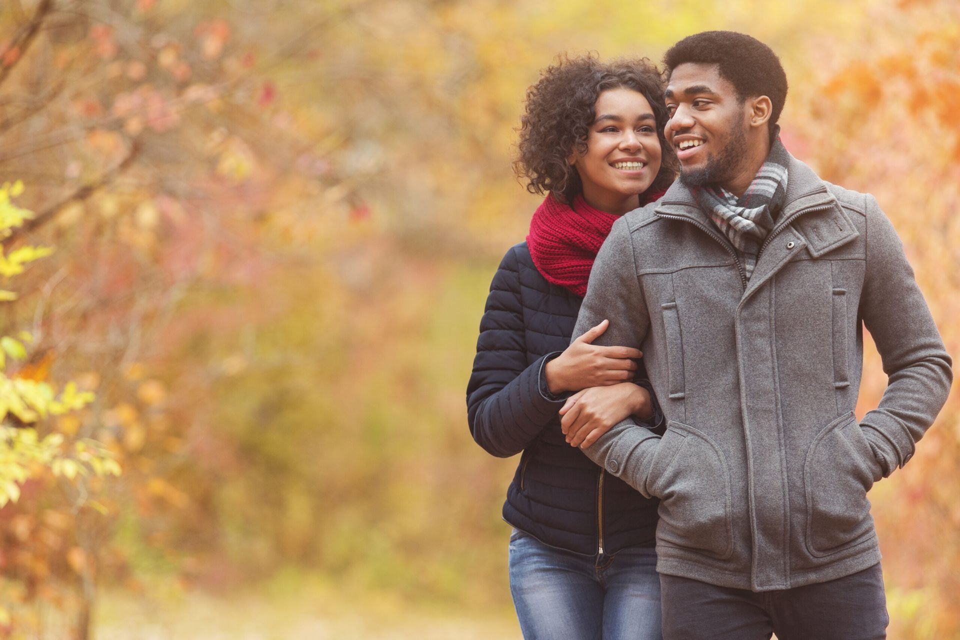 Dating Bio Article | Couple smiling and embracing outdoors in autumn, with colorful fall leaves in the background