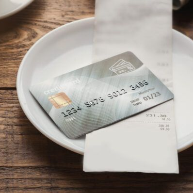 Credit card on a receipt in a white bowl on a wooden table.