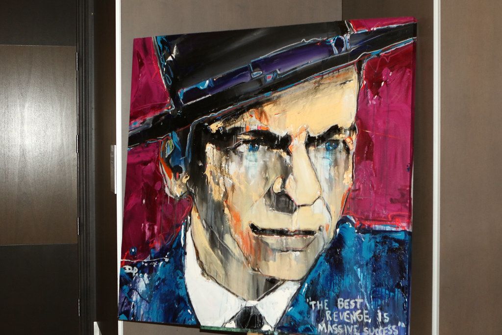Painting of Frank Sinatra in a fedora and suit with pink background and quote