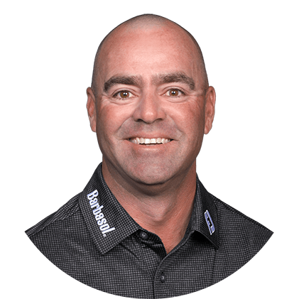 Bald man, smiling, wearing a dark collared shirt with 