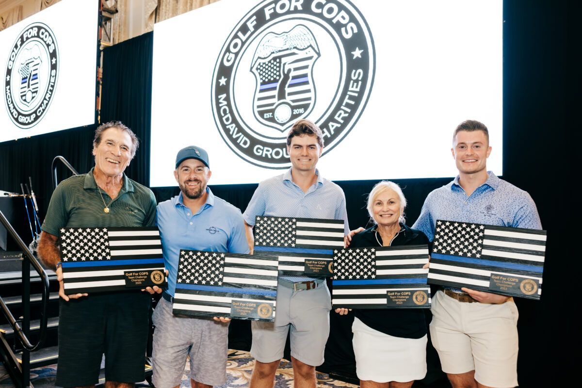 Five people holding framed American flags with thin blue lines at an event labeled