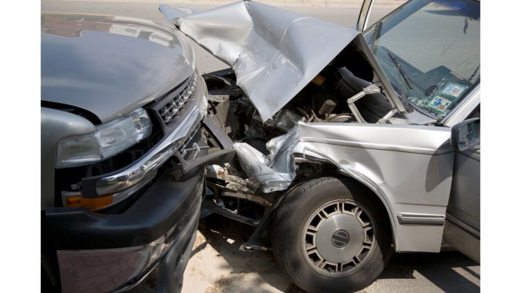 A close-up of a severe head-on car collision between two silver vehicles with significant front-end damage.