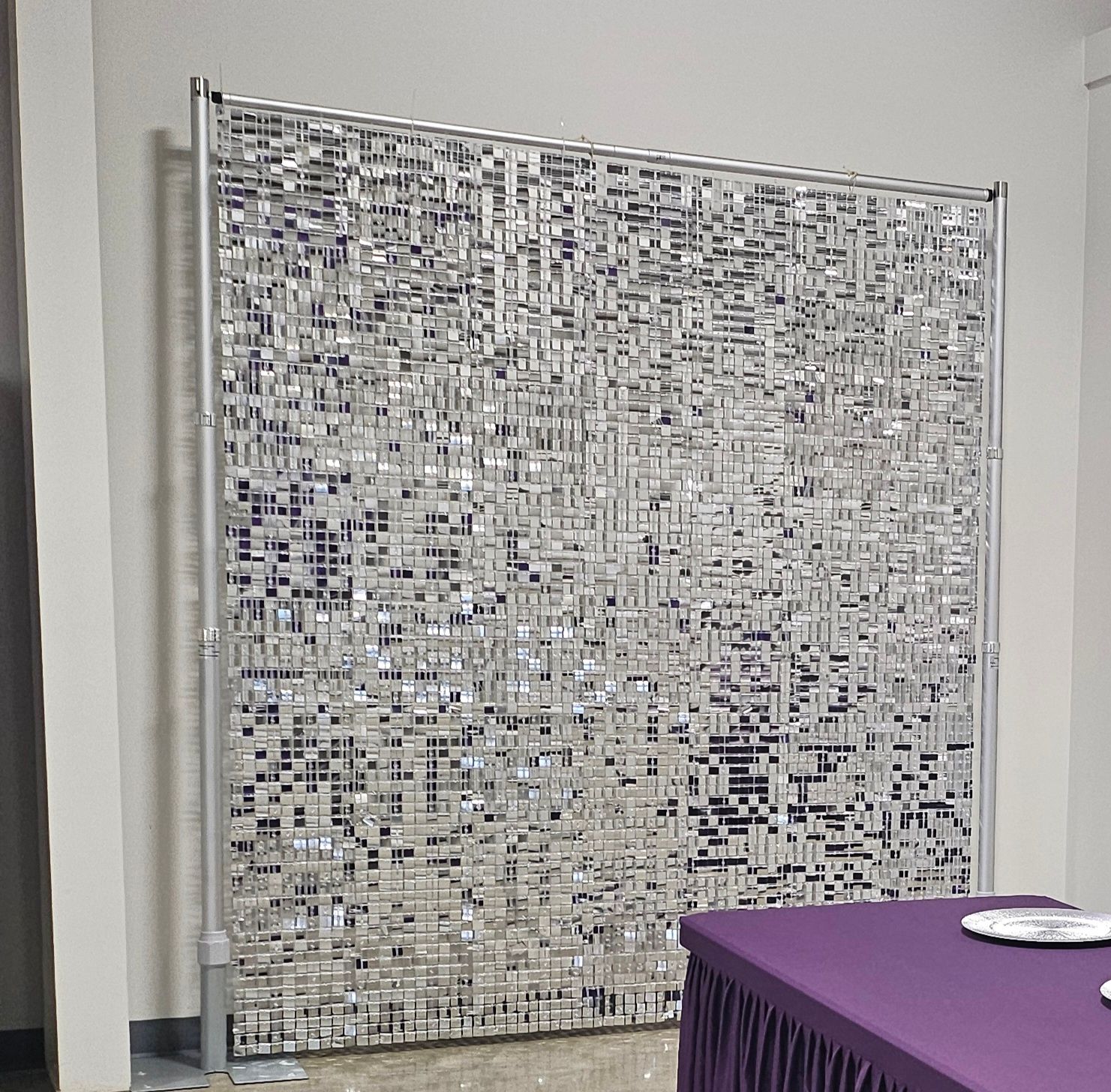 Large abstract white-and-gray mosaic panel against a wall, with a purple table in the foreground