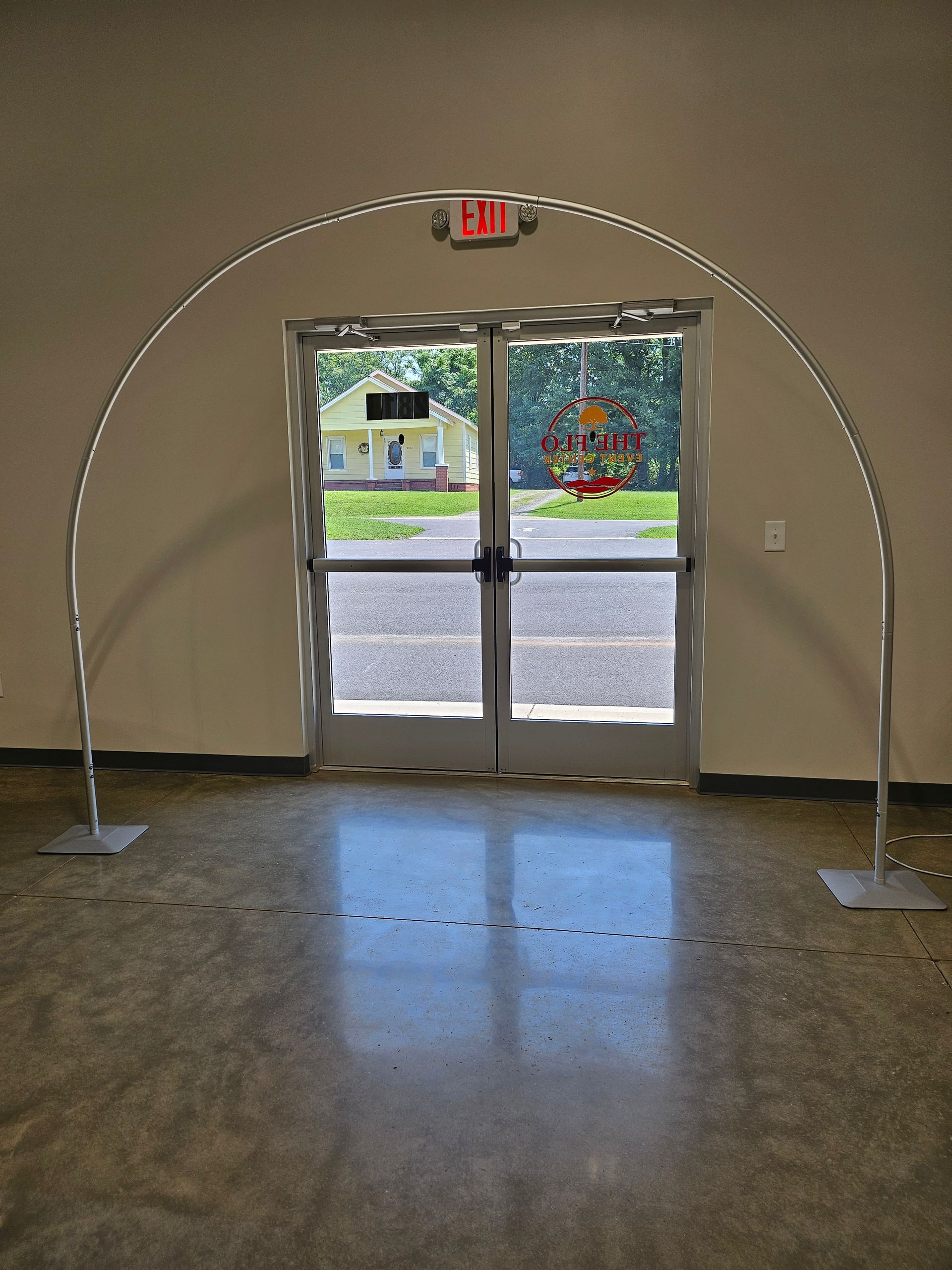 Metal archway over double doors in a hallway, with an exit sign above and daylight visible outside