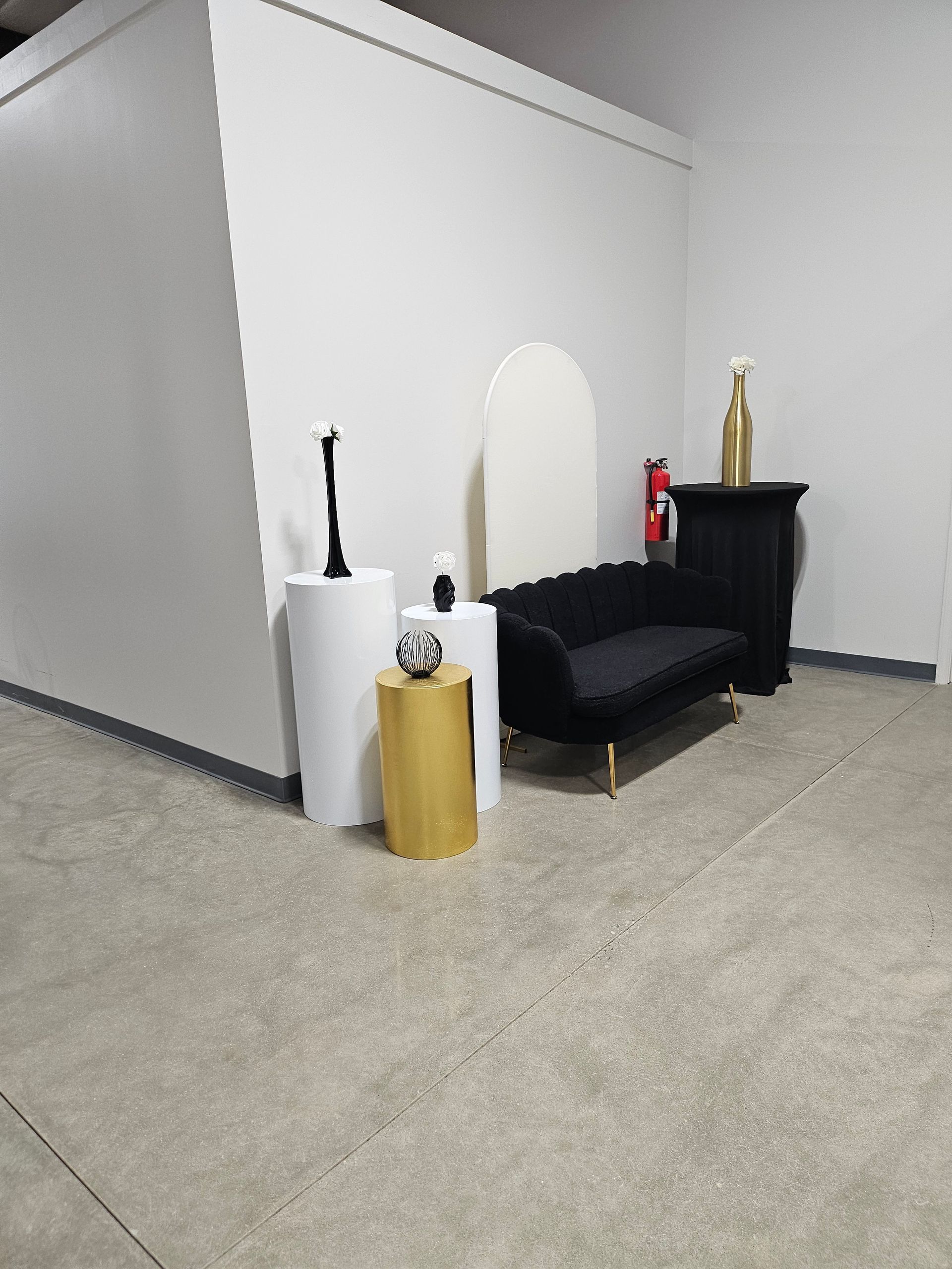Lobby seating area with black sofa, white walls, and decorative pedestal tables on a carpeted floor