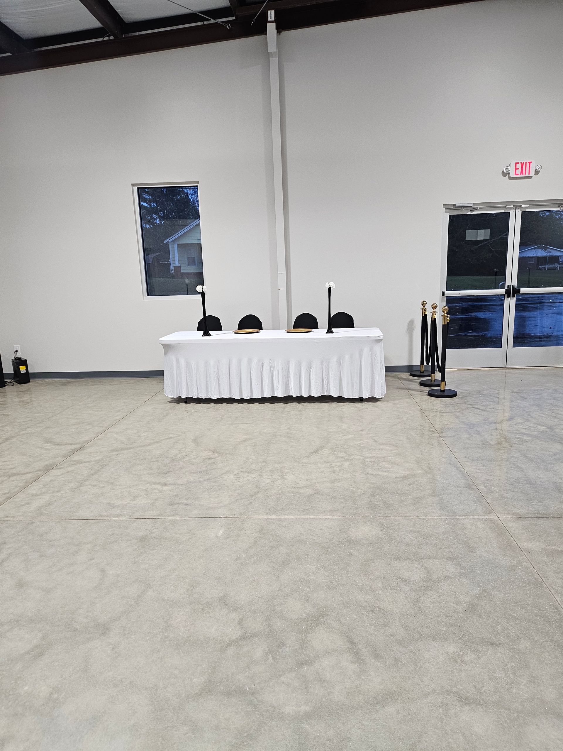 Empty conference room with a white-draped table, chairs, and blue double doors in the background