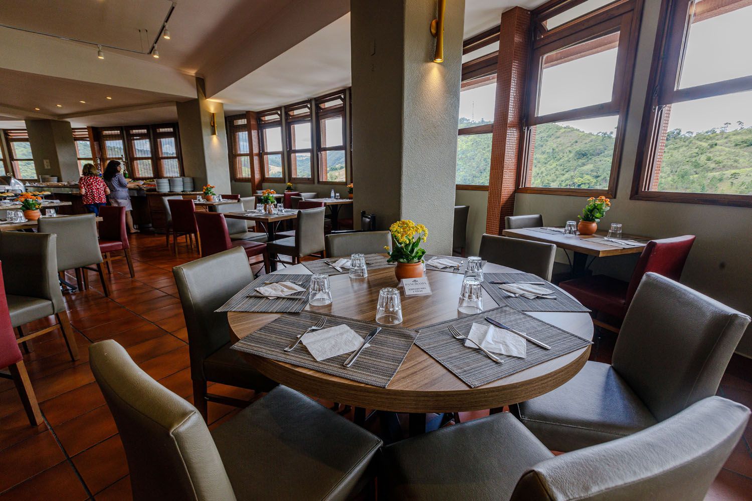 Um restaurante com mesas e cadeiras e muitas janelas.