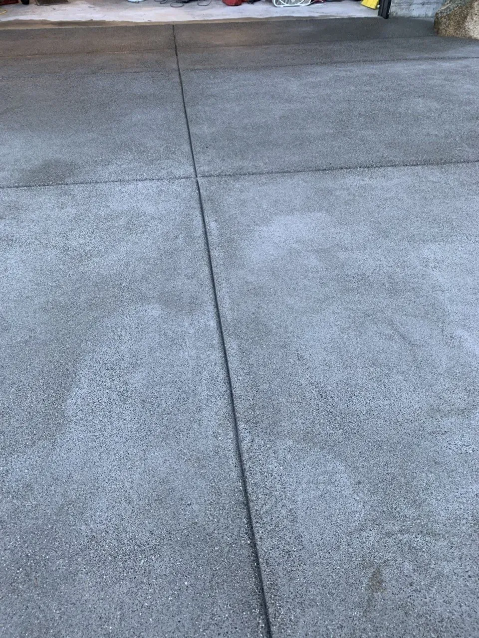 Cracked concrete driveway with a long seam line running down the center