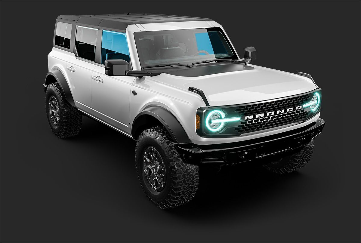 A white four-door Ford Bronco SUV with glowing blue headlights, positioned at an angle against a dark grey background.