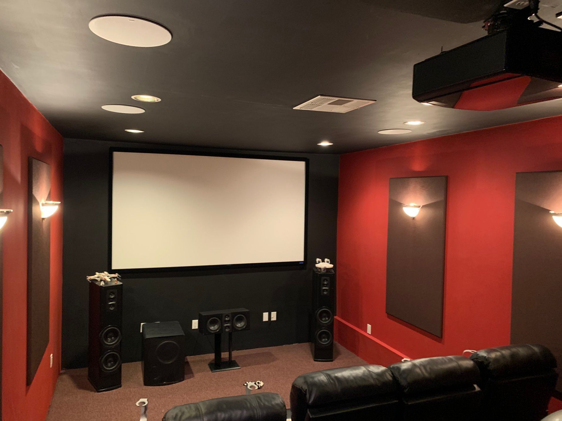 Un cine en casa con paredes rojas y una pantalla blanca.