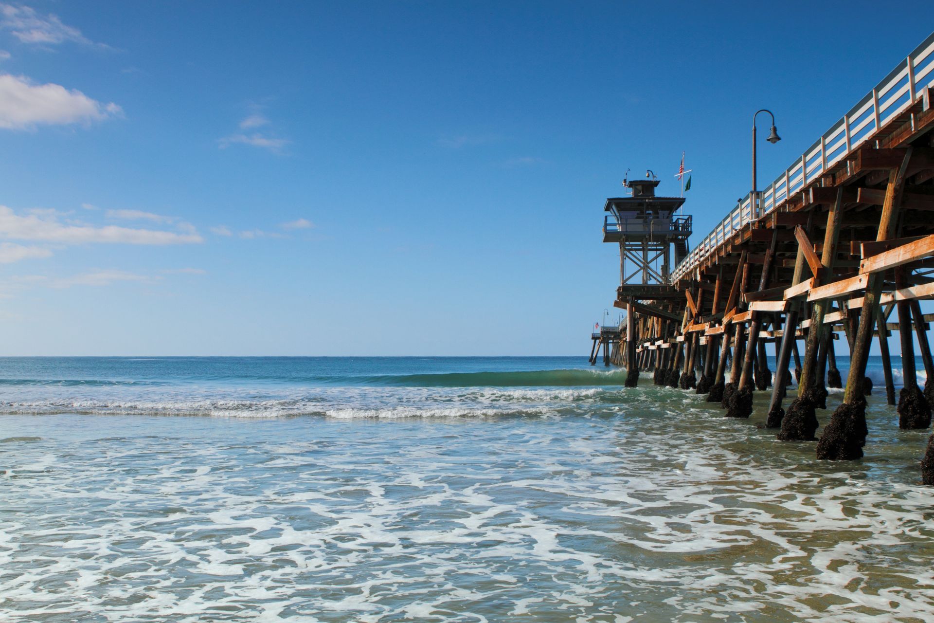 A pier leading into the ocean on a sunny day.