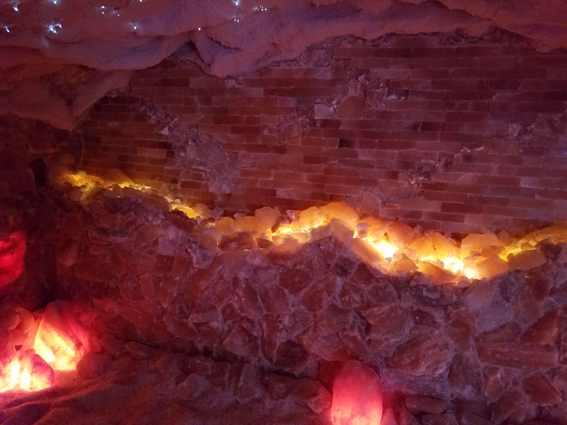 Illuminated salt cave wall, orange and pink tones, with rough texture.