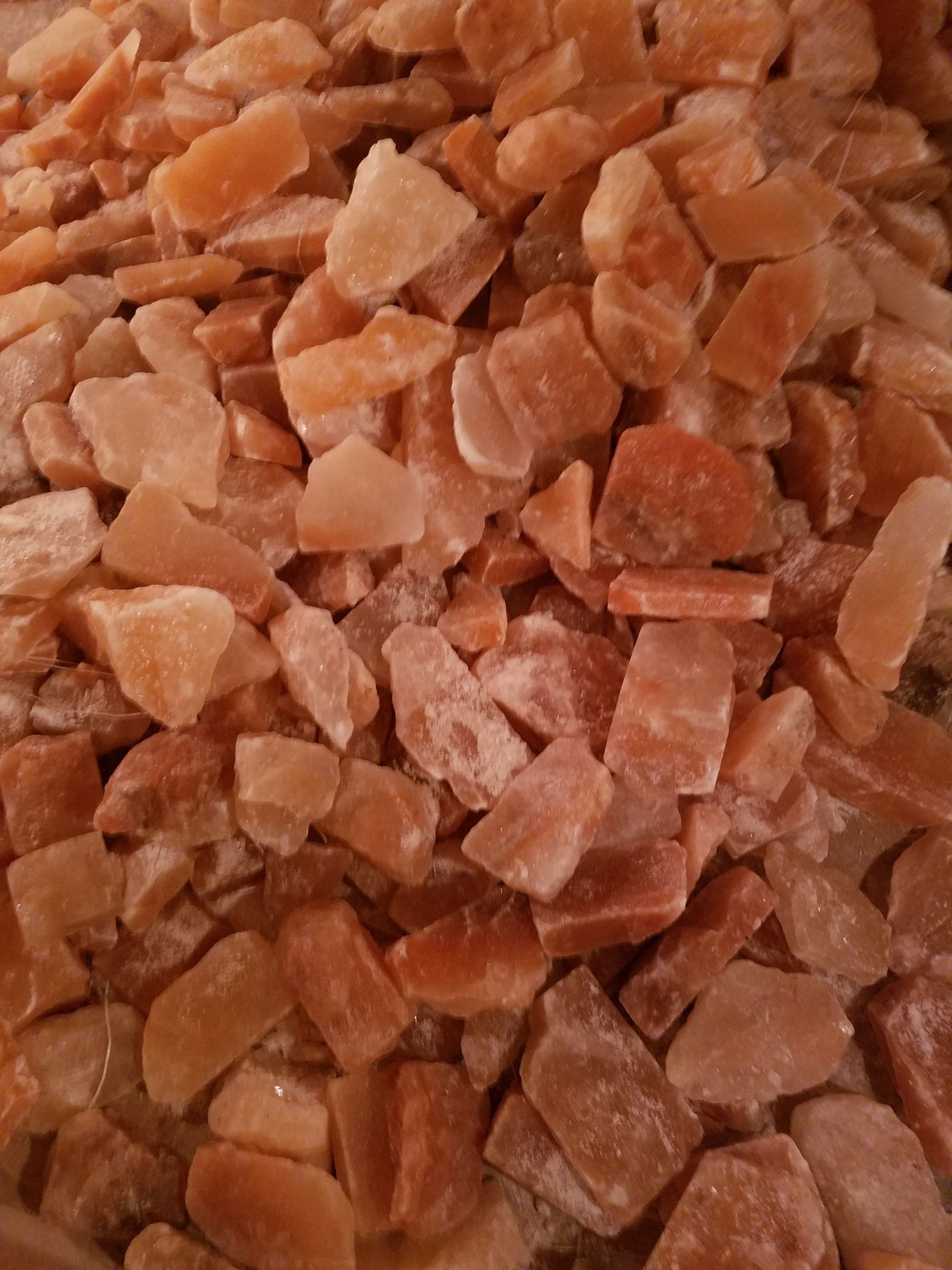 Pile of roughly chopped, light orange-pink Himalayan salt crystals.