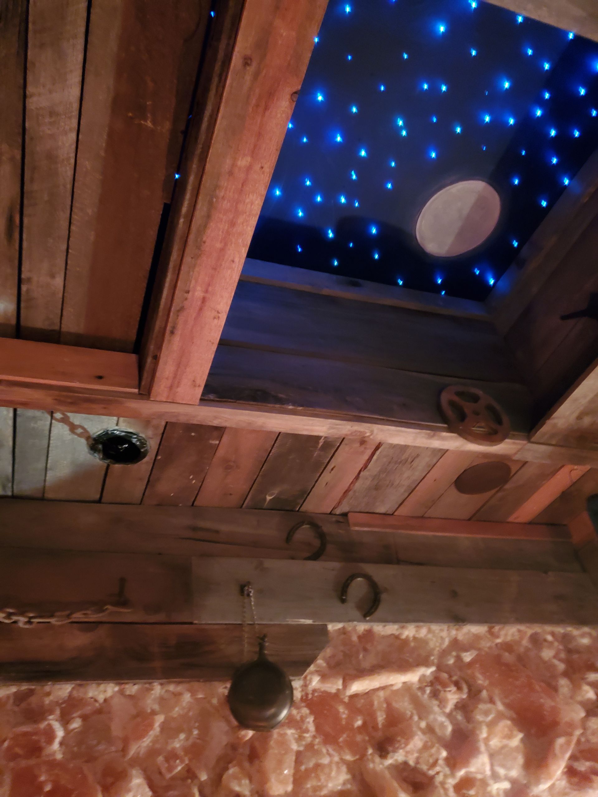 Rustic ceiling with a starry sky effect, a moon, and exposed wooden beams.