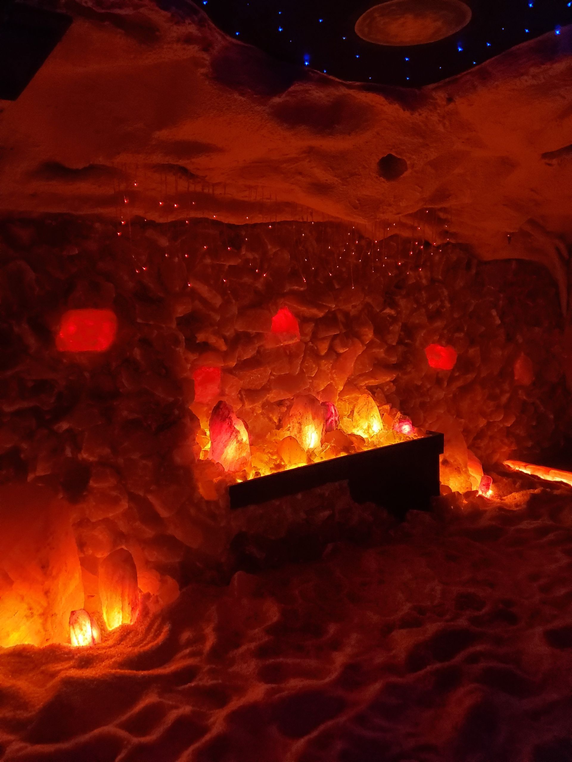 Dramatic red-lit cave interior with glowing crystals and a dark rectangular structure.