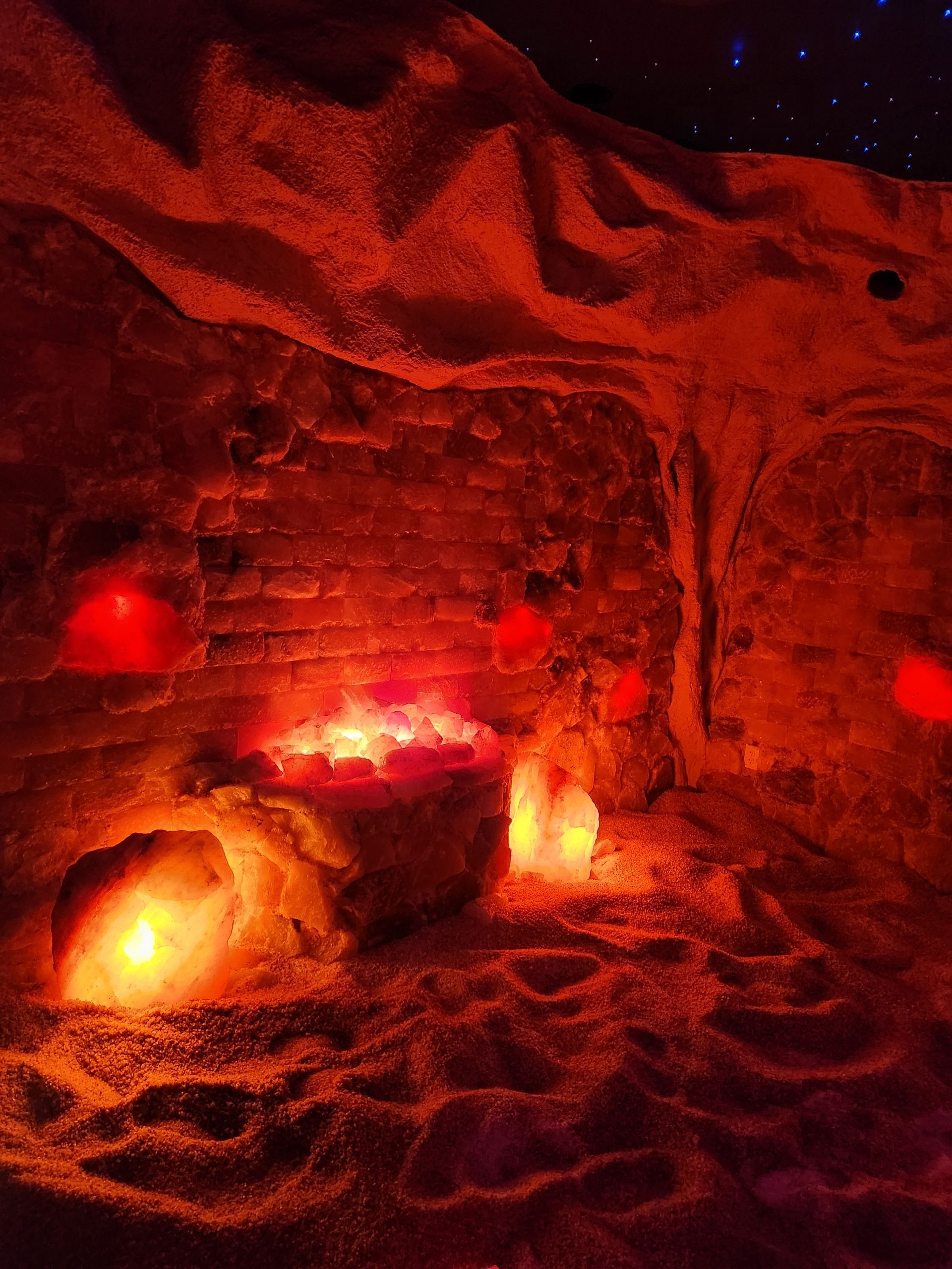 A cave filled with rocks and candles is lit up with red lights.
