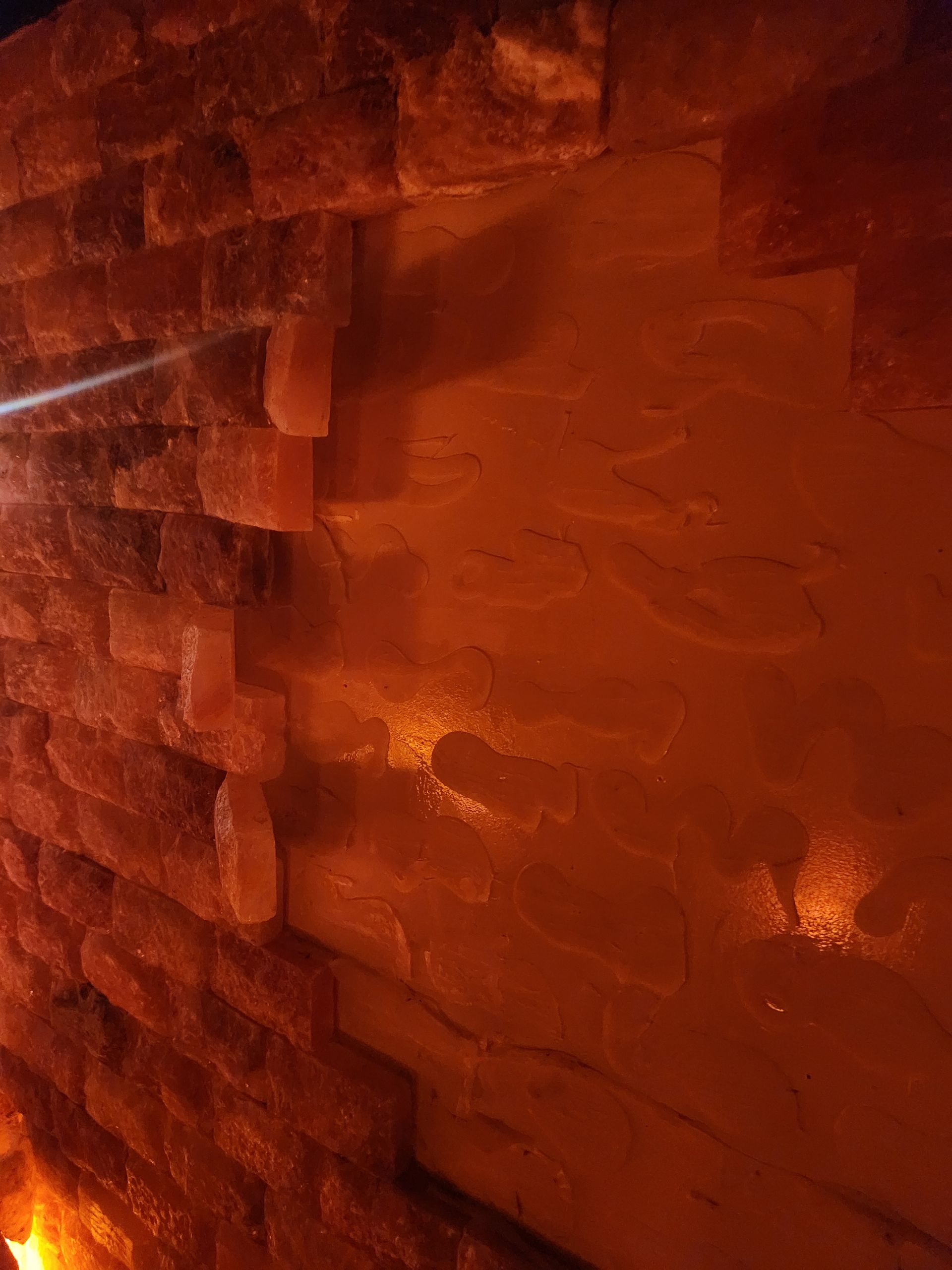 Brick wall with embedded salt crystals, illuminated with warm orange light.