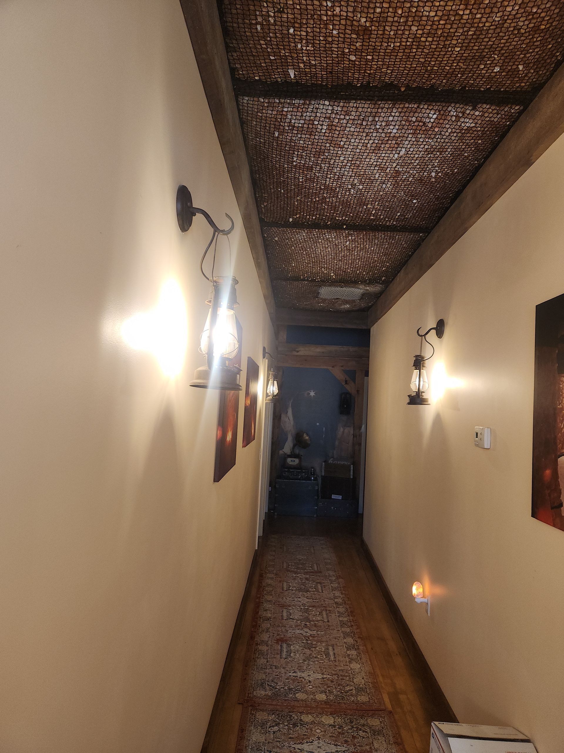Narrow hallway with patterned ceiling, wall sconces, and a runner rug.