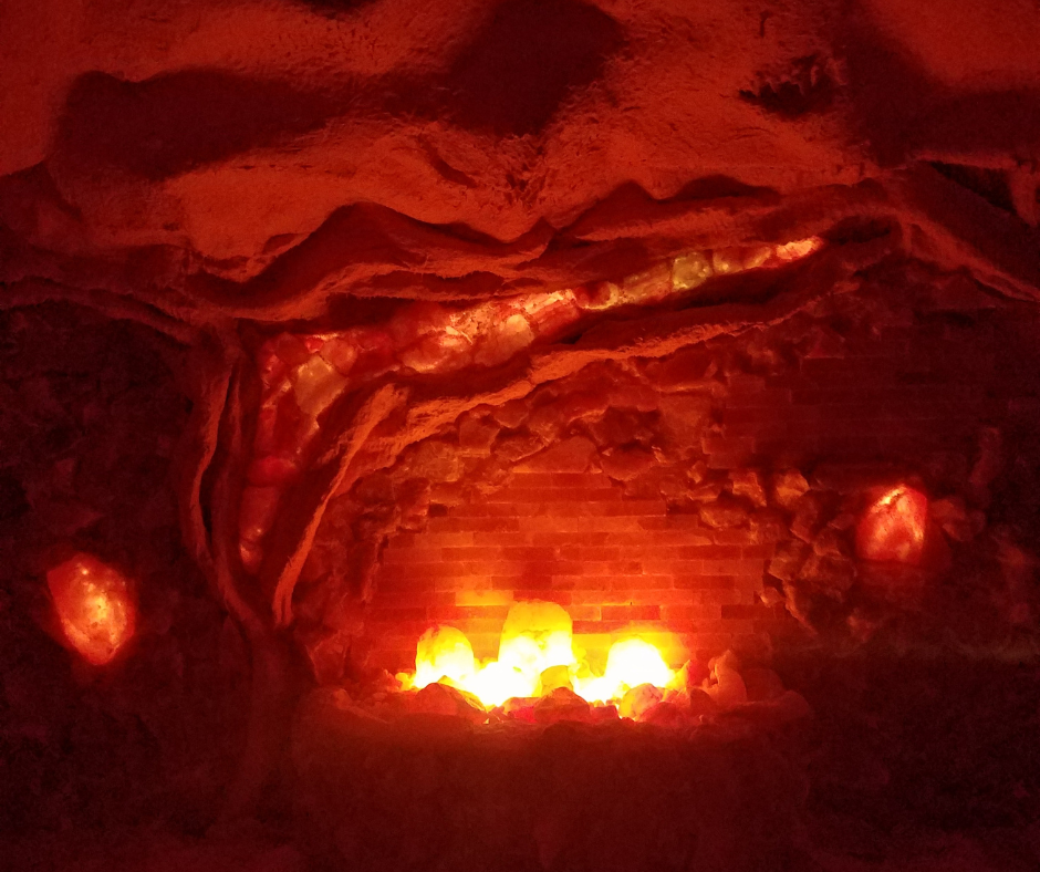 Red-lit cave fireplace with bright flames and rocky, arched walls