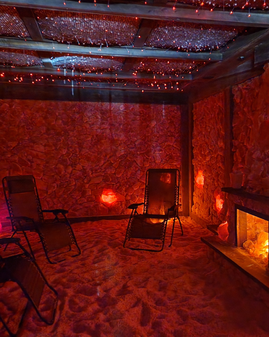 Salt therapy room with pink salt walls, chairs, and fireplace glow.