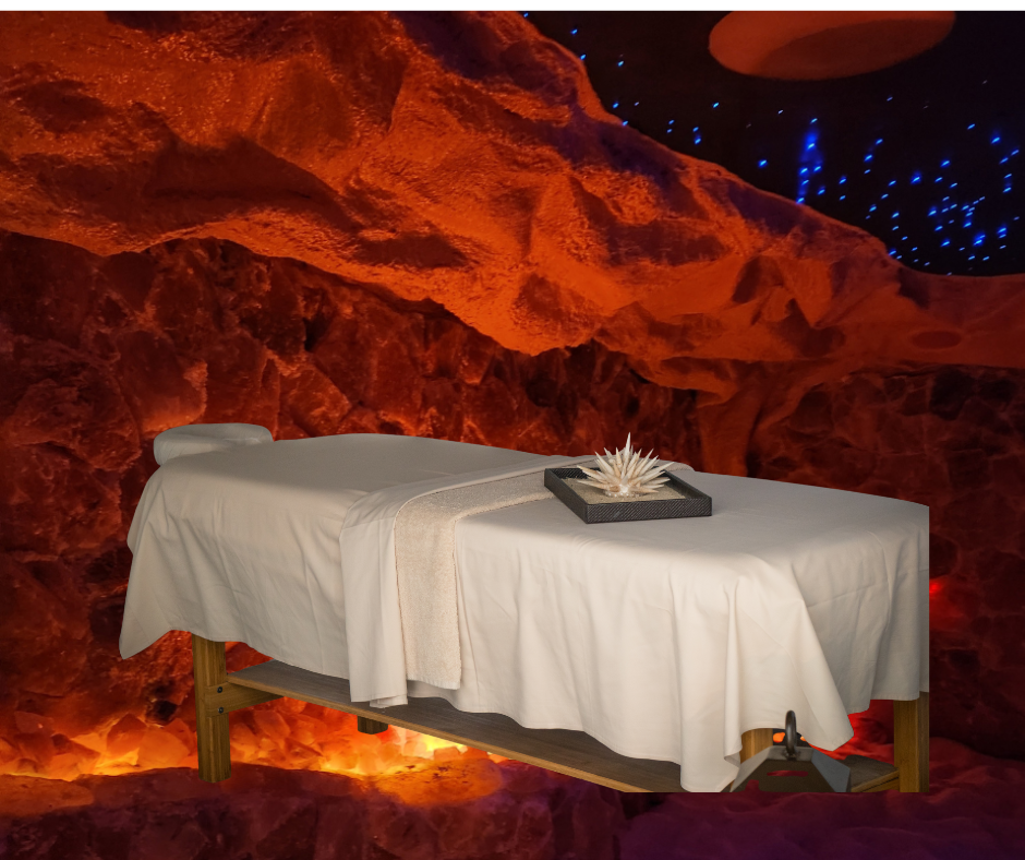 Massage table in a dimly lit salt cave with orange glow and decorative tray.