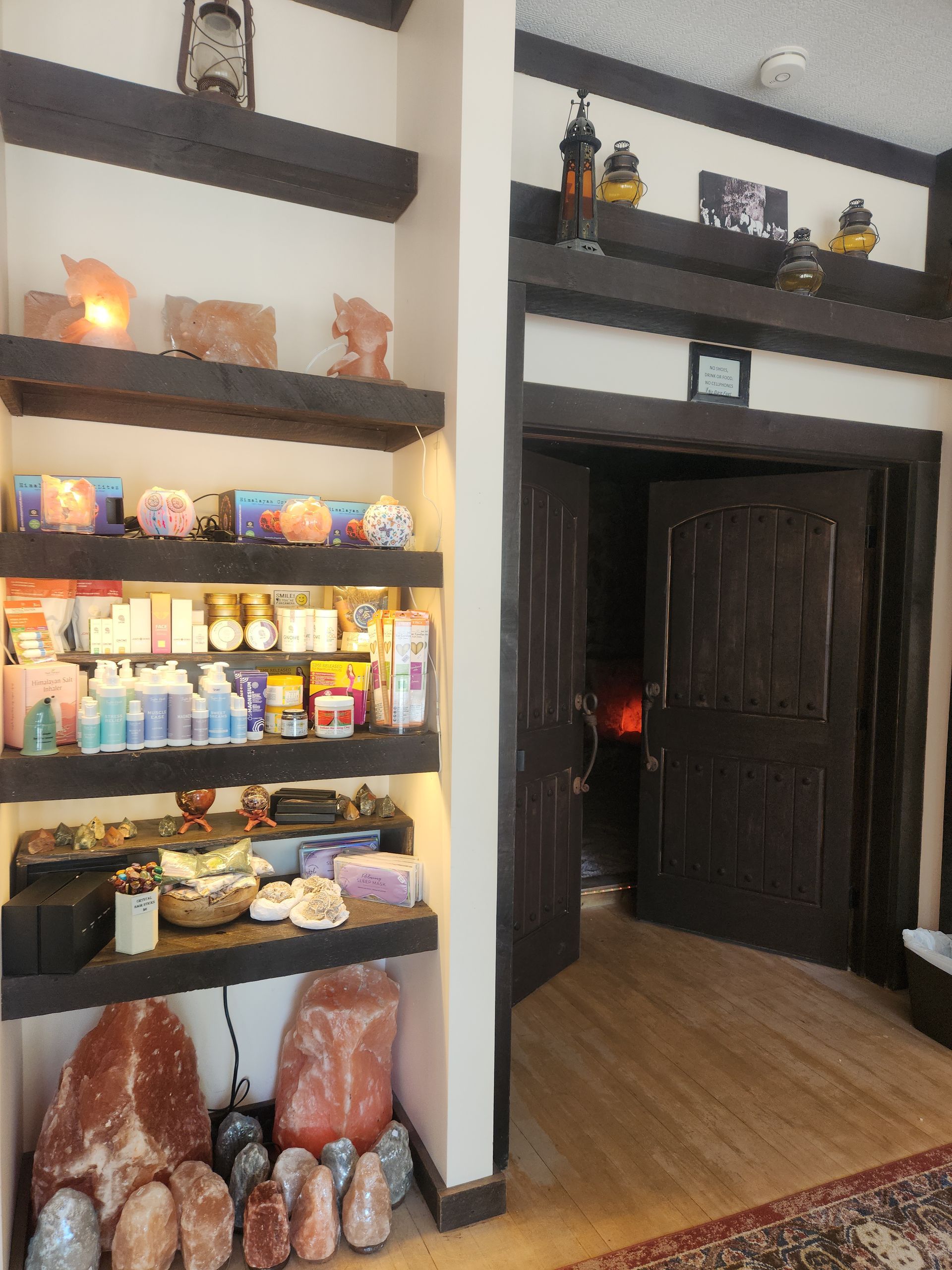 Shelves displaying various spa products, illuminated by lights, next to a dark wooden doorway.