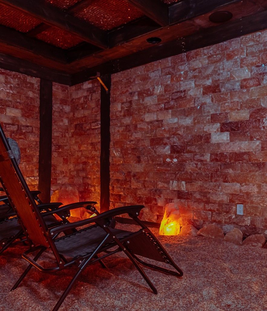 Salt therapy room with lounge chairs against a pink salt brick wall.