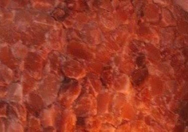 Close-up view of a surface with irregular, reddish-orange shapes, possibly a salt block or crystallized material.