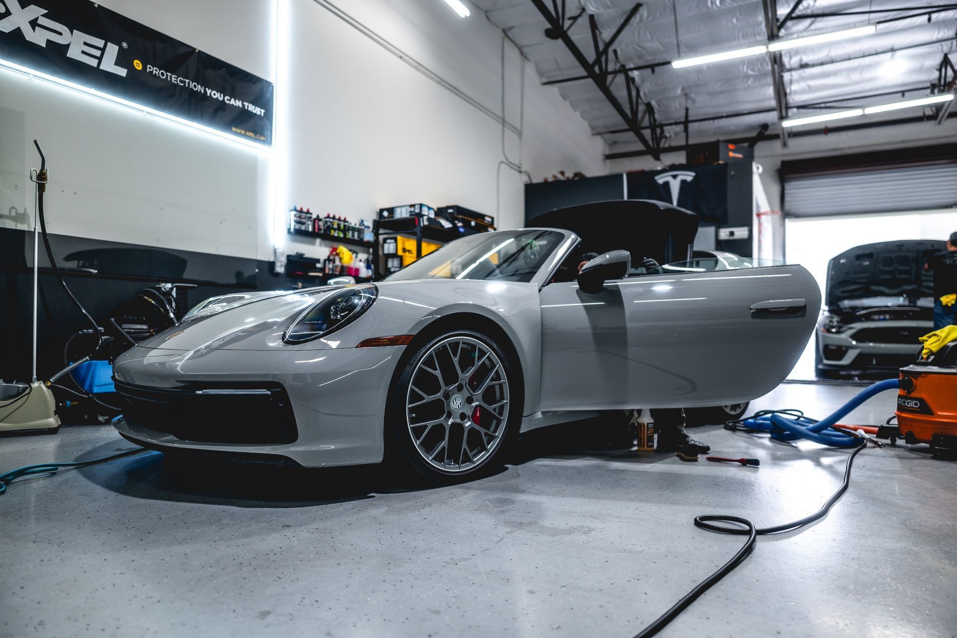 Gray Porsche convertible in a garage with door open.