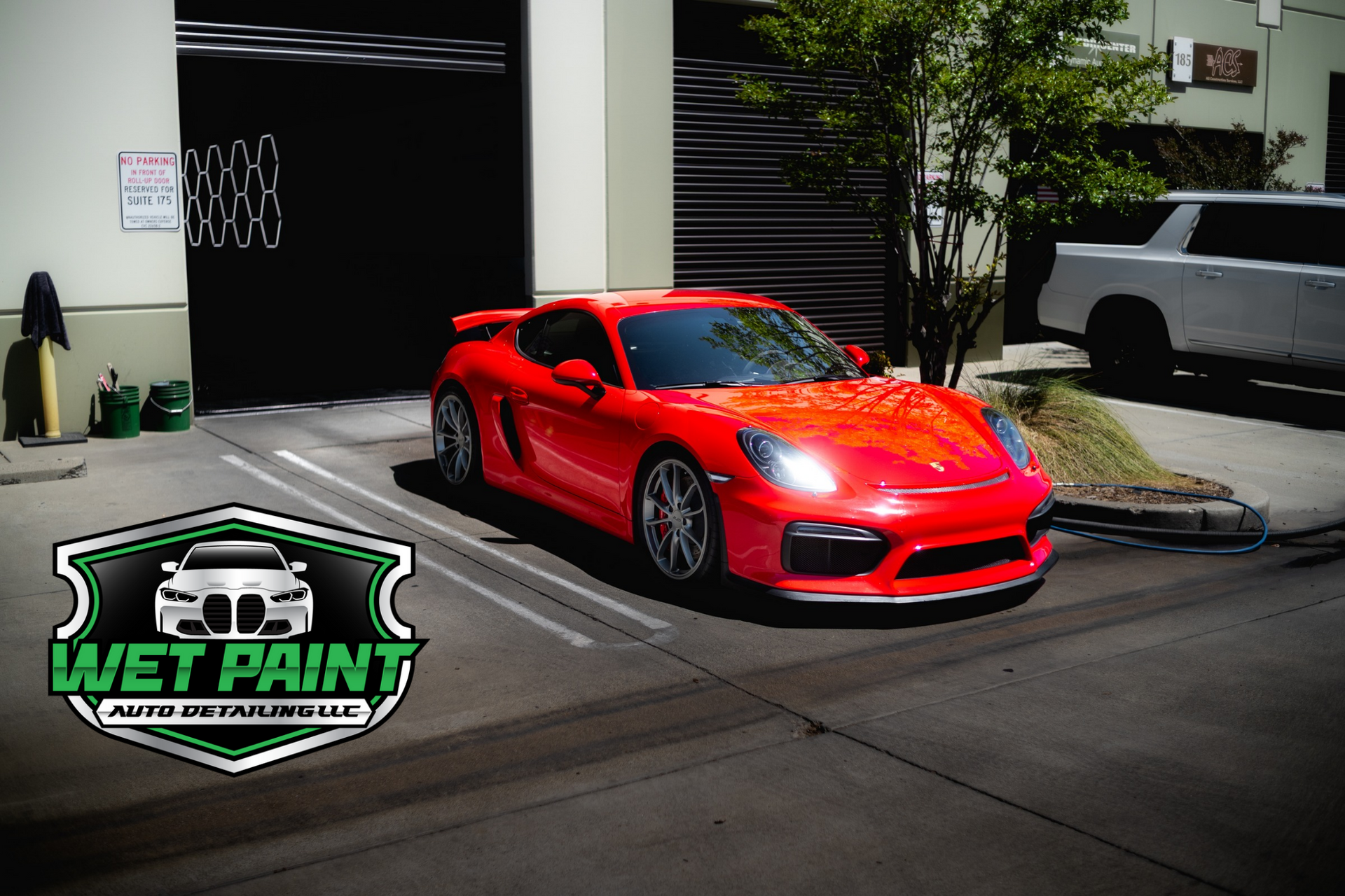 Red Porsche parked in front of Wet Paint Auto Detailing business; bright, sunny day.