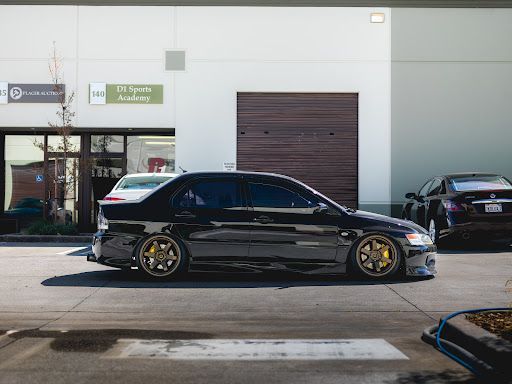 Slammed black Mitsubishi Evo with ceramic coating parked outside a detailing shop
