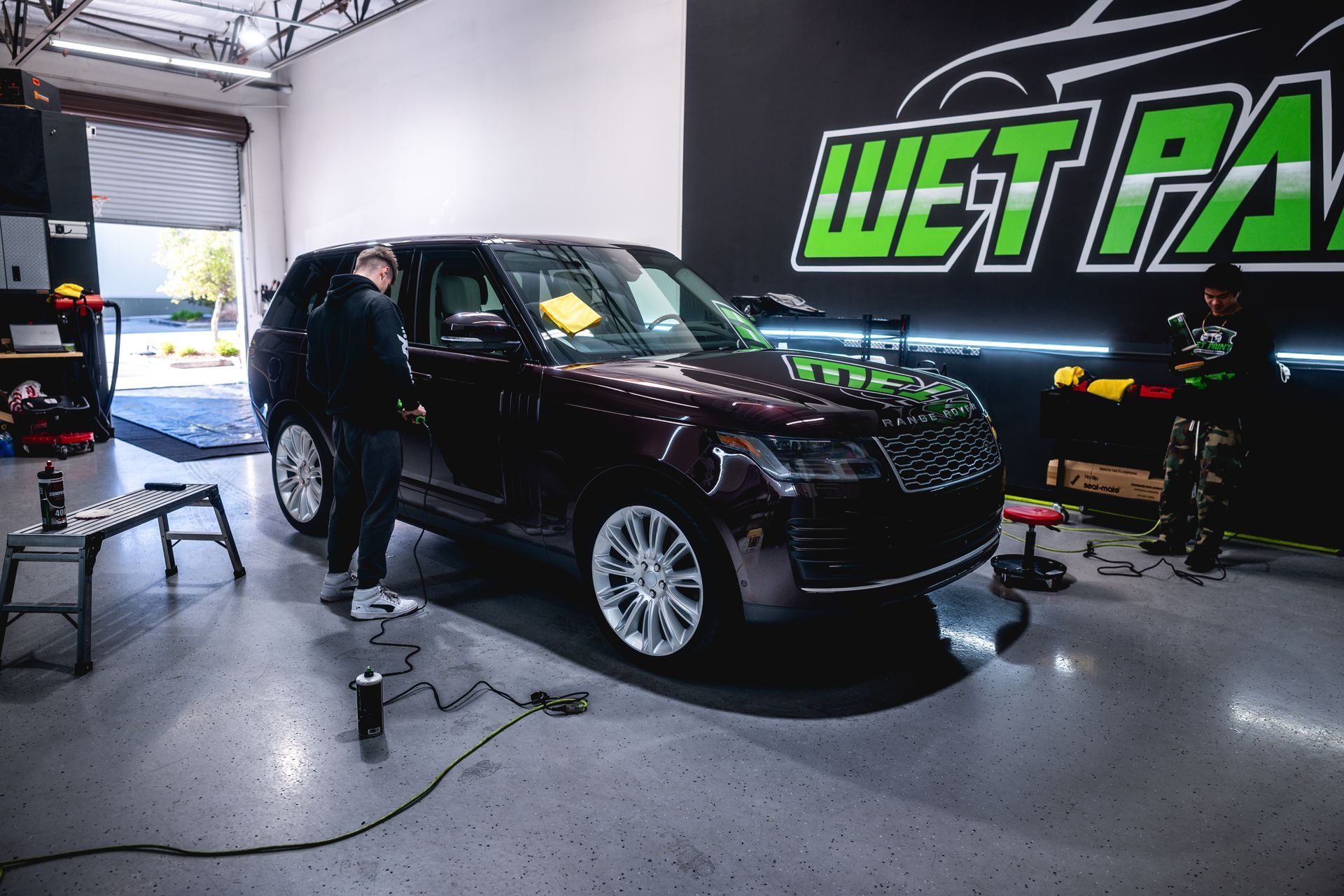 A man is standing next to a range rover in a garage.