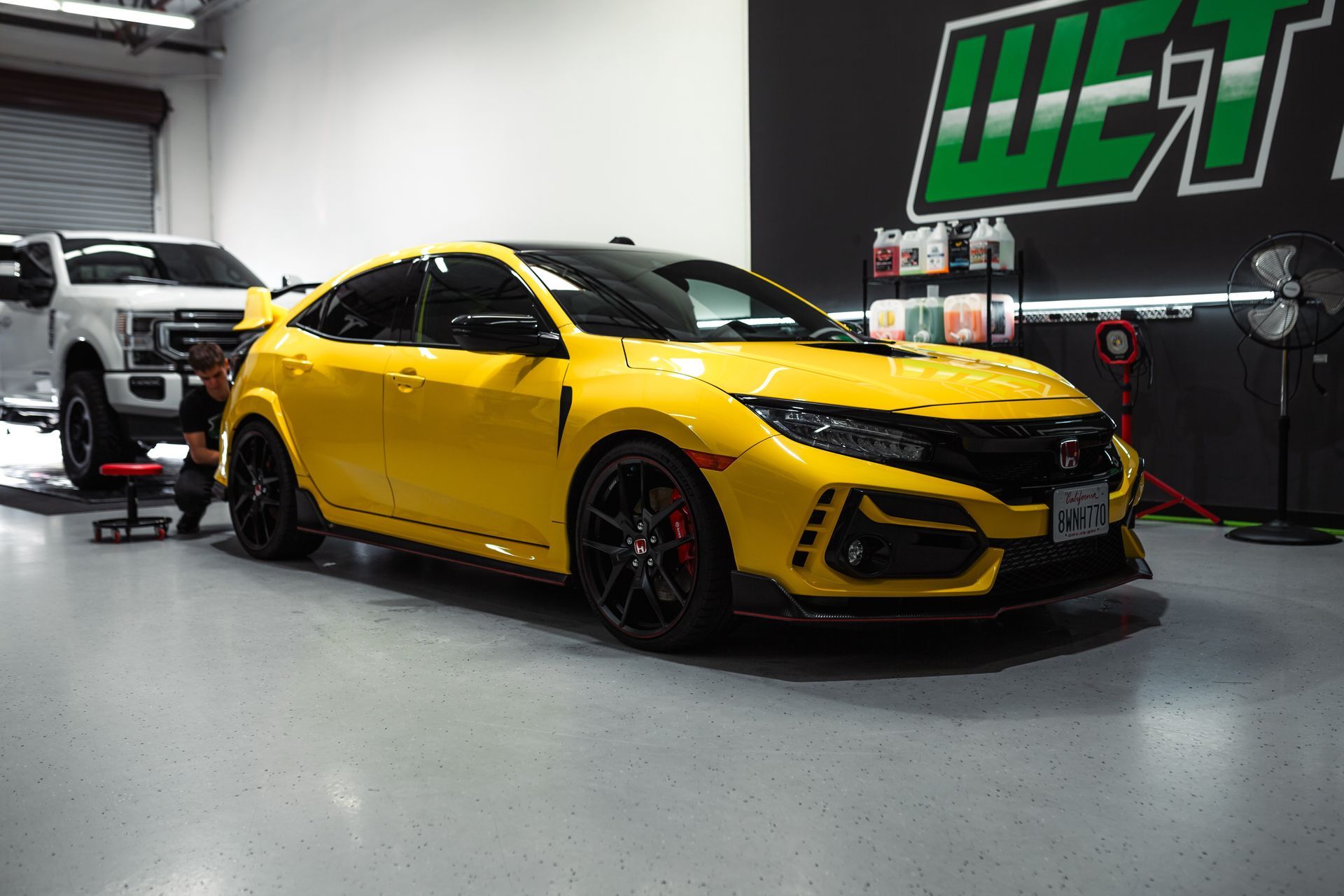 A yellow honda civic type r is parked in a garage.