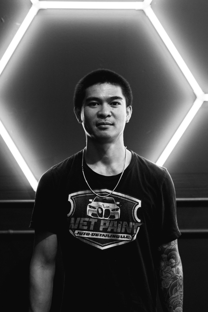 A man in a black shirt is standing in front of a wall with lights on it.