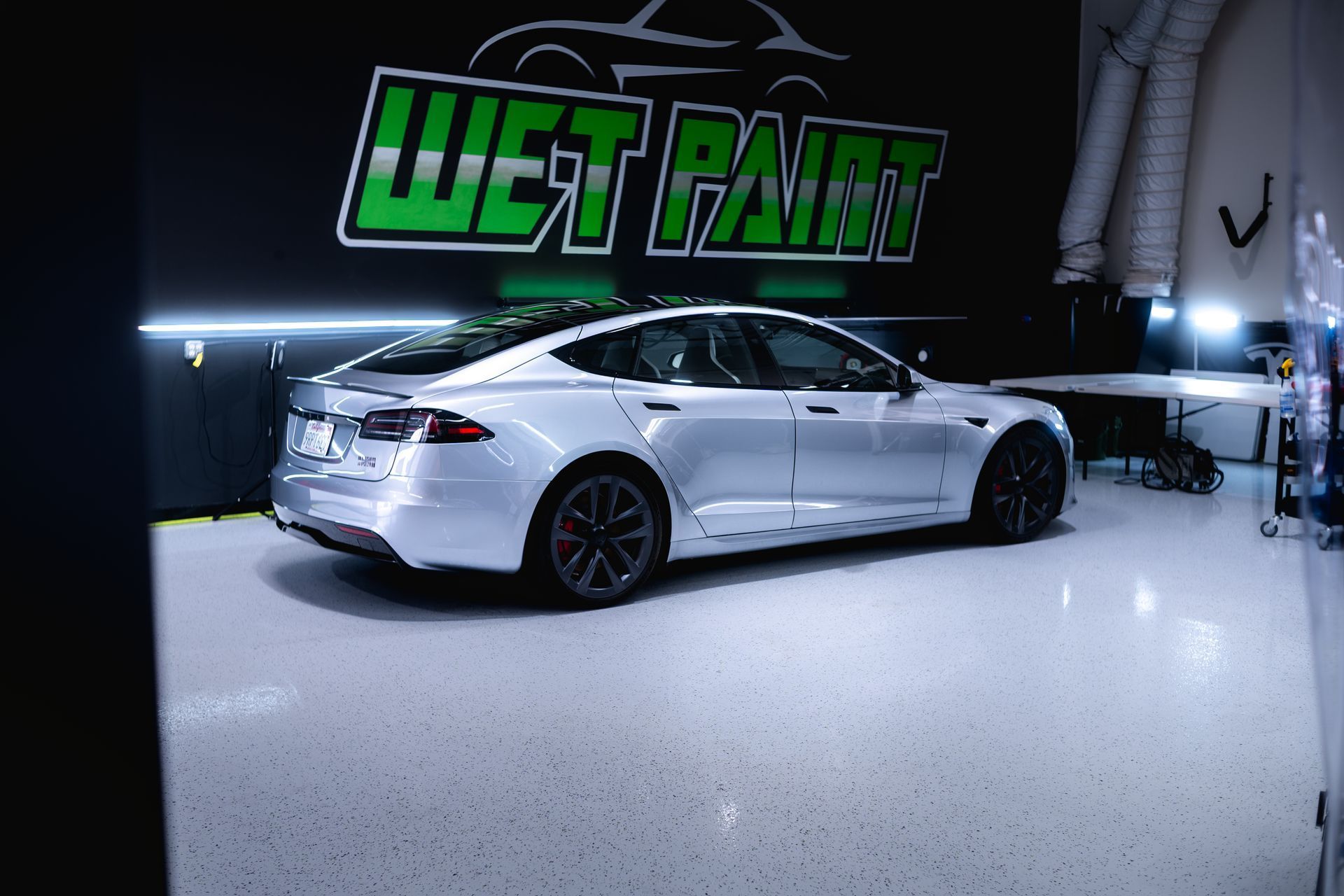 A silver Tesla parked in a clean garage with a 