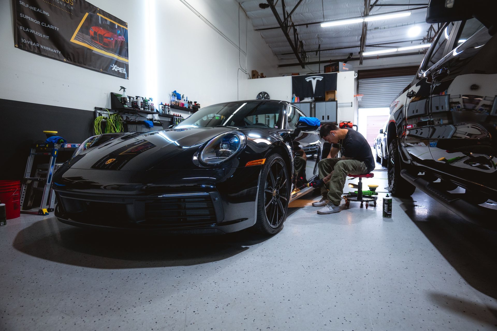 A man is working on a black car in a garage.