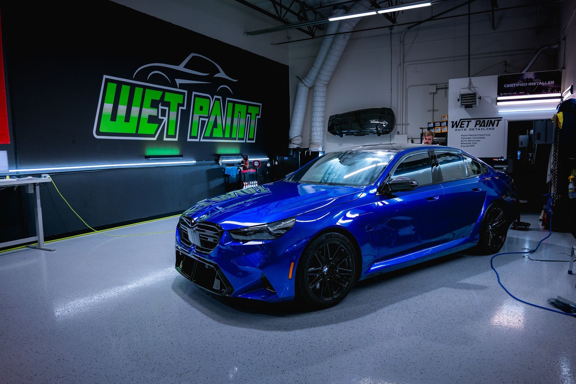 Blue BMW sedan inside a car detailing shop; 
