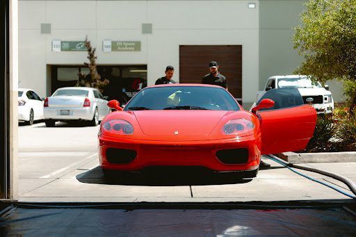 Red Ferrari parked outside a detailing studio with paint protection film applied