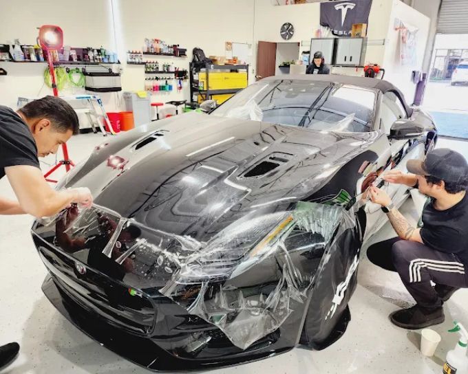 Paint protection film being applied to a black sports car in Roseville, CA