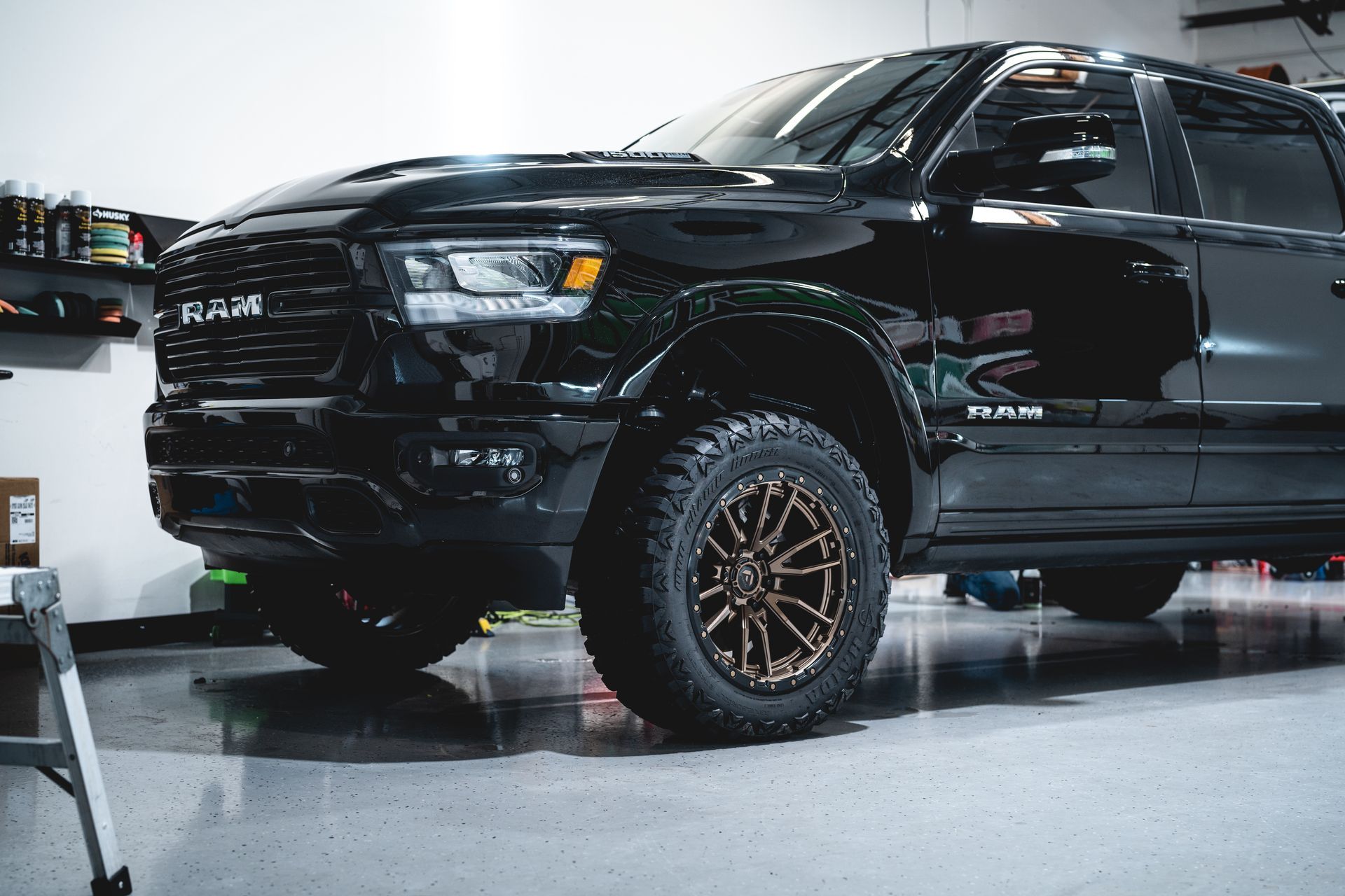 Black lifted pickup truck with bronze wheels in a garage or showroom