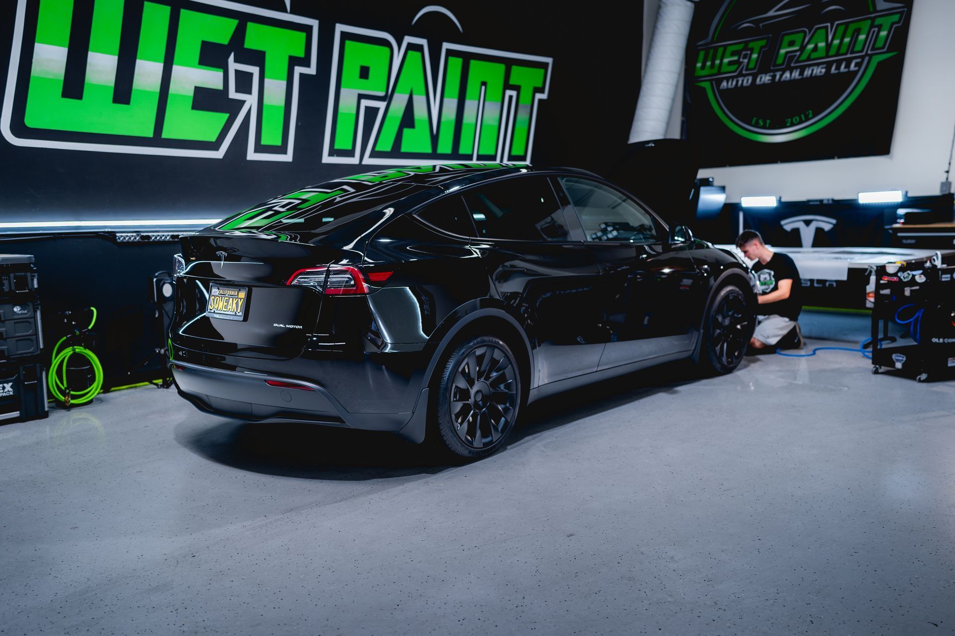 A black Tesla parked inside a shop with a green 