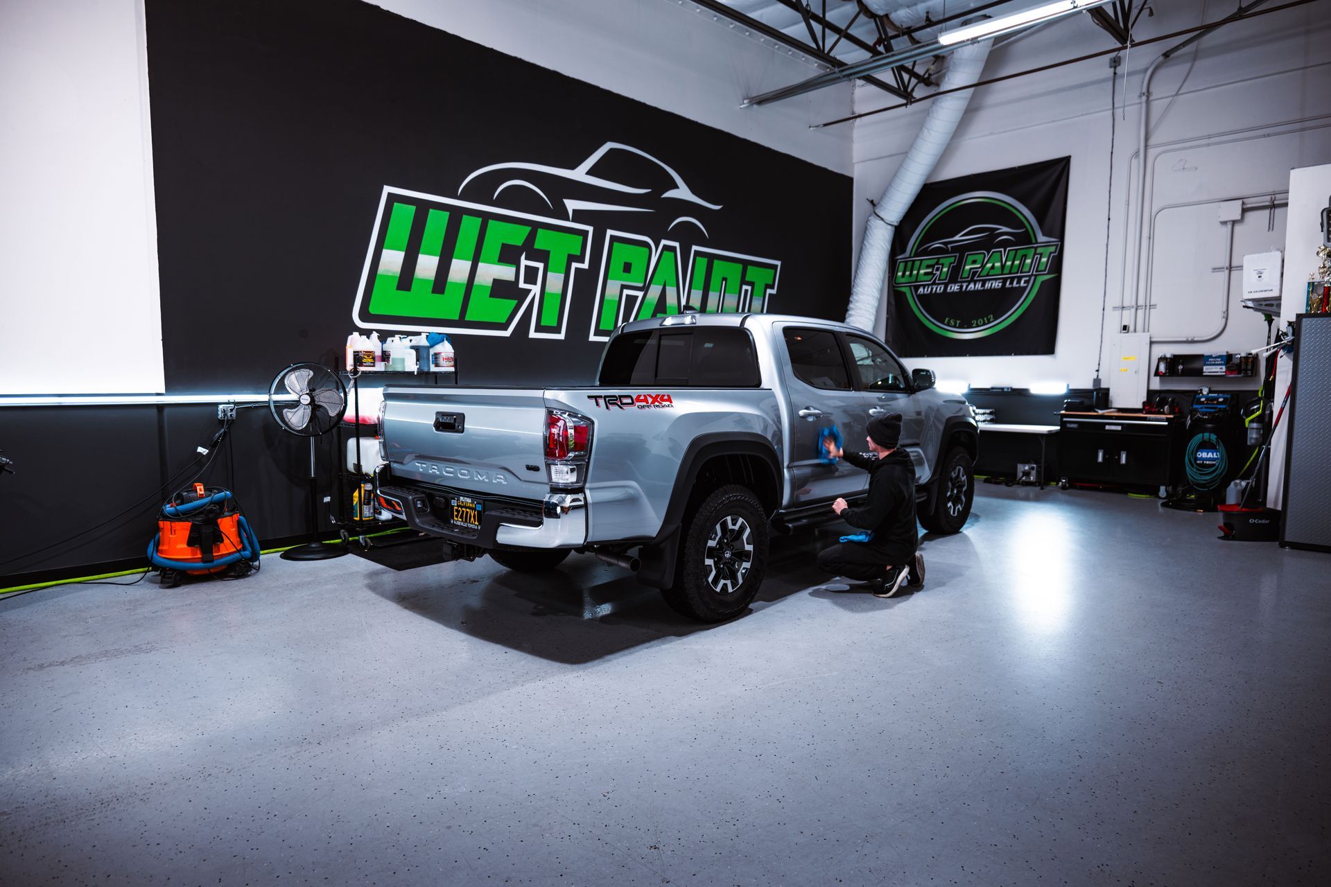 Silver pickup truck inside an auto shop with a large green