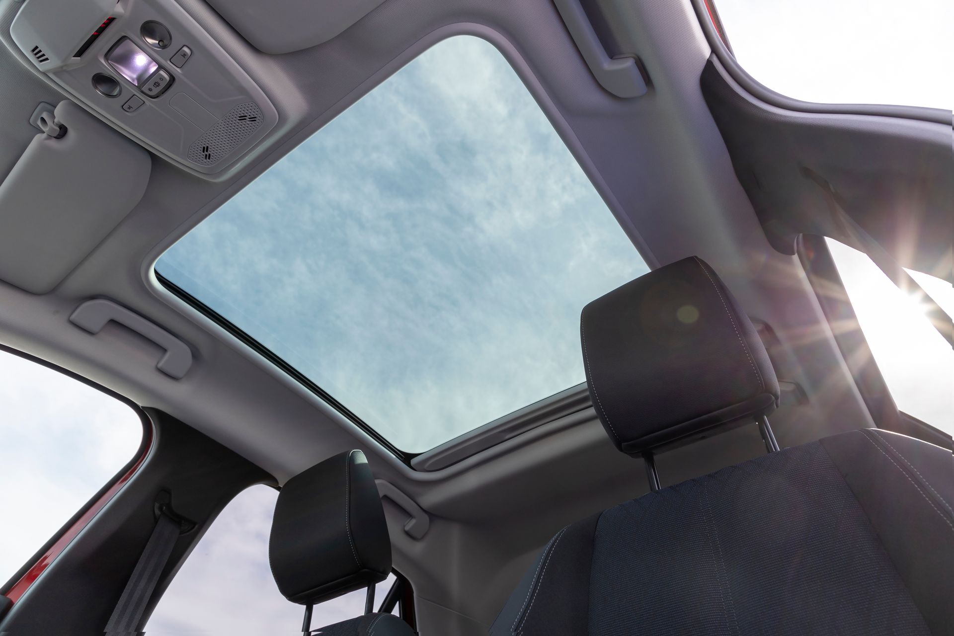 Car interior with sunroof, front seat headrest, and sunlight streaming in