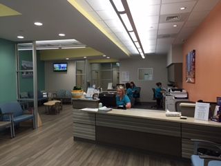 A brightly lit medical office reception area with staff working behind a desk. 