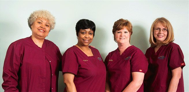 Image of pediatric staff, all smiling and  wearing maroon scrubs.