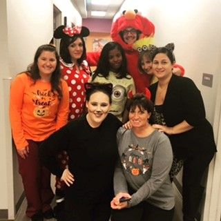 A group of medical professionals at Advocare Broomall Pediatric Associates in Halloween costumes gathered in a hallway. 