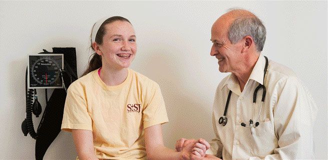 Male doctor with a young patient who is smiling.