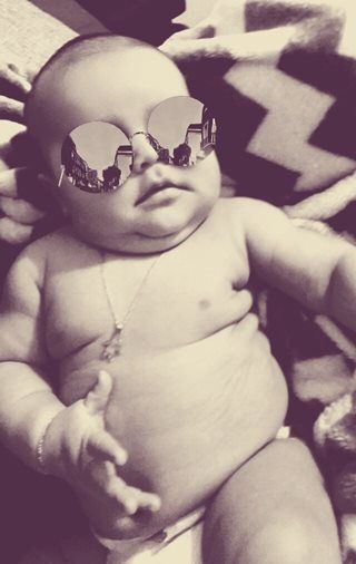 Photo of baby on a blanket with sunglasses on.