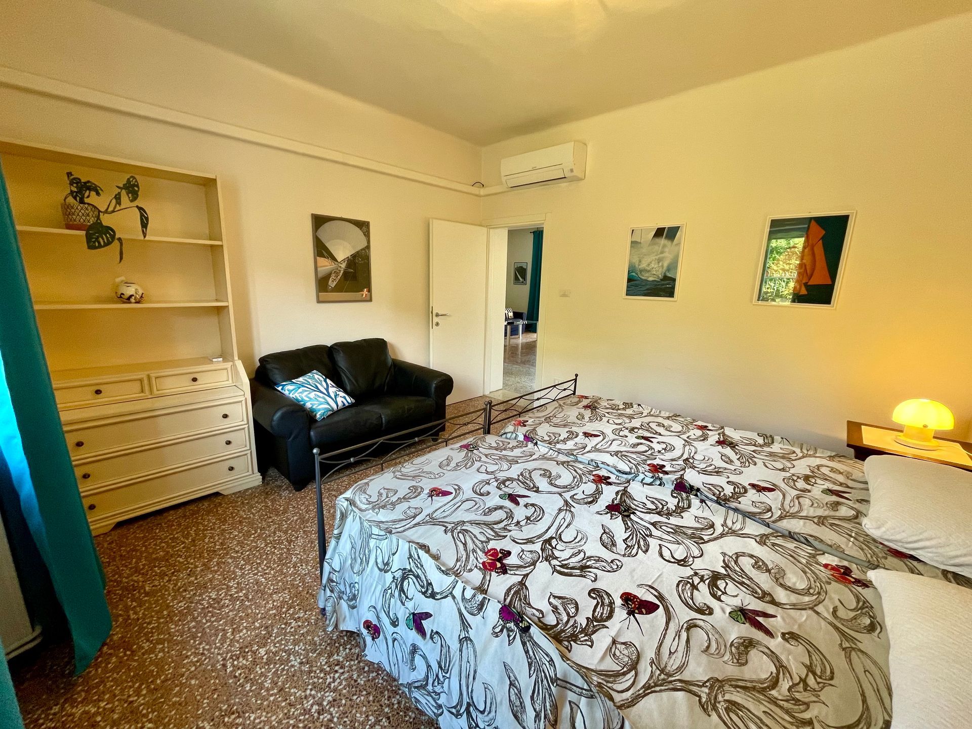 Camera da letto doppia con due letti singoli, divano in pelle nera e mobile a cassettoni bianco