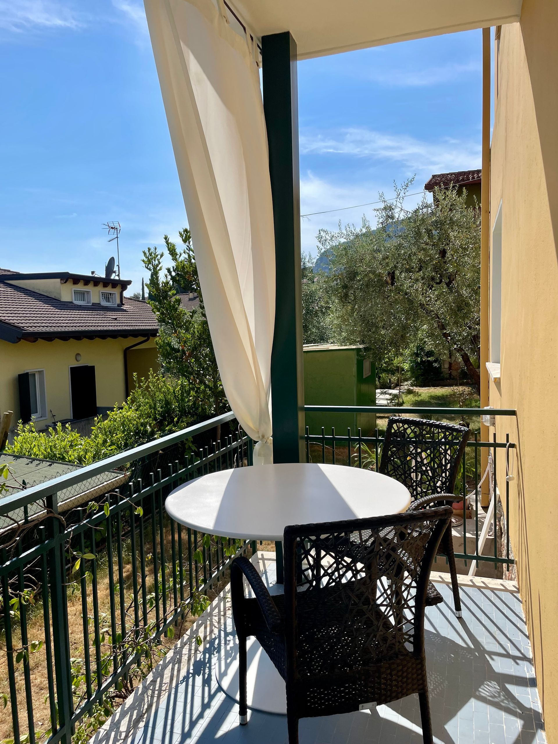 Balcone coperto con tavolo e sedie e tende bianche per il sole